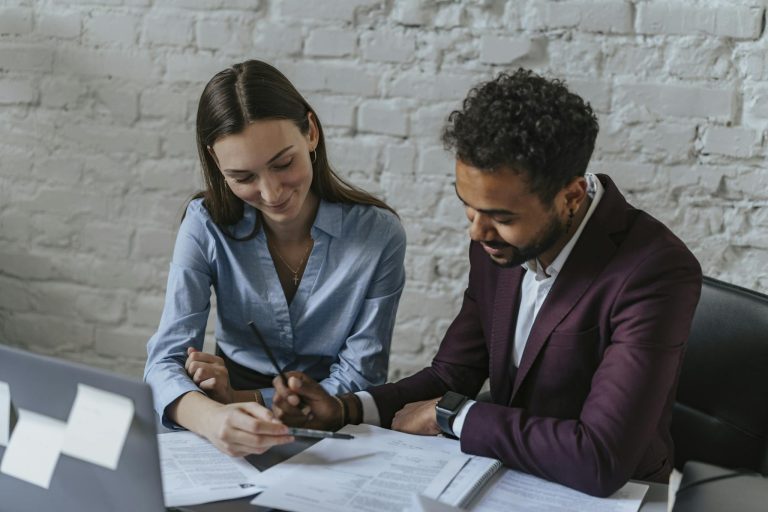 Two business professionals collaborating on documents in an office setting.